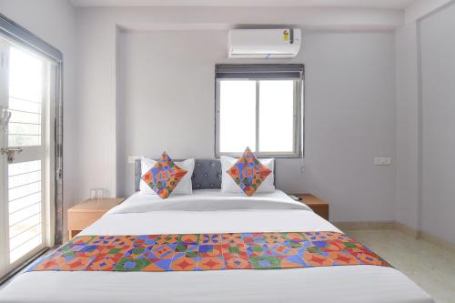 a bedroom with a bed with a colorful blanket on it at FabHotel Ojas Inn in Pune