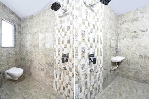 a bathroom with a shower with a toilet and a sink at FabHotel Ojas Inn in Pune