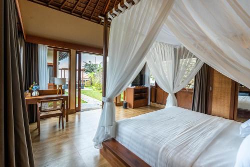 a bedroom with a canopy bed and a desk at Shankara Munduk Bali in Munduk