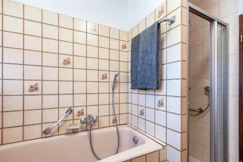 a bathroom with a tub and a shower with a blue towel at Landzeit in Efringen-Kirchen