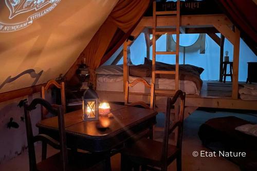 a room with two beds and a table in a tent at Gîte du sorcier - Etat Nature in Magnières