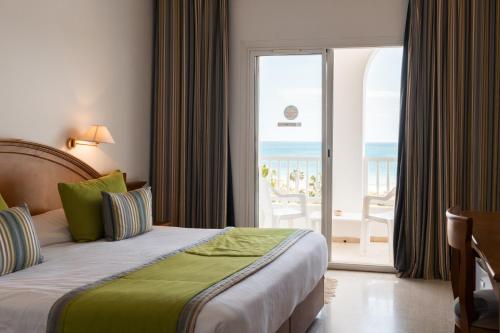 a bedroom with a bed and a balcony with the ocean at Yadis Hammamet in Hammamet