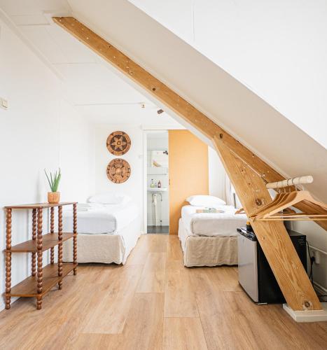 a attic bedroom with two beds and a staircase at Hotel Nine in Zandvoort