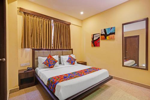 a bedroom with a large white bed with colorful pillows at FabHotel Pride - Electronic City in Bangalore