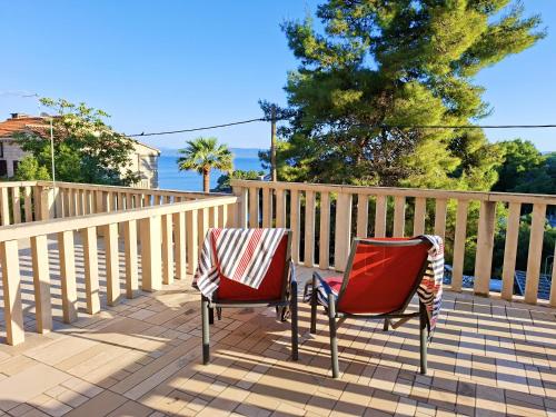 two red chairs sitting on a patio with a fence at Sea View Apartments in Selca