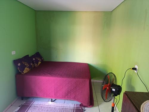 a bedroom with a pink bed and a fan at cantinho do descanso in Dourados