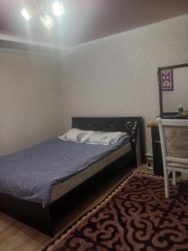 a bedroom with a bed and a table and a chair at Abylay Guesthouse in Jangy-Talap
