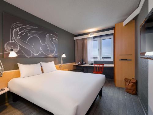 a bedroom with a large white bed and a desk at ibis München Parkstadt Schwabing in Munich
