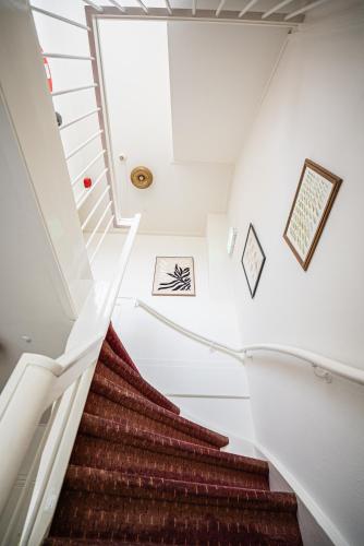 a winding staircase in a house with white walls and red carpet at Hotel Nine in Zandvoort
