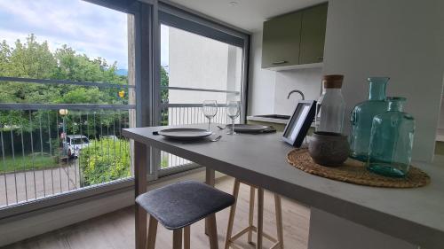 a kitchen with a table with two glasses and a window at Studio moderne Climatisé Meylan centre proche CHU in Meylan