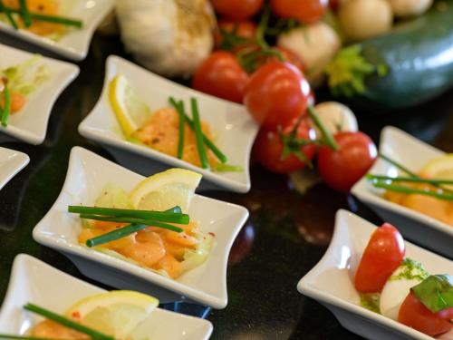 a table topped with plates of food with tomatoes and vegetables at Mercure Hotel Berlin City in Berlin