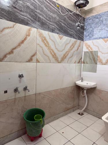 a bathroom with a shower and a sink and a bucket at RADHA DEVI GUEST HOUSe in Juliāsar