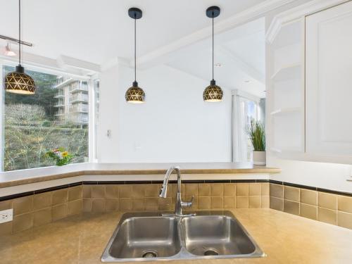 a kitchen with a sink and a window and pendant lights at Panoramic Ocean & Fairway Views At Sayward Hill in Victoria