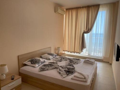 a bed in a bedroom with a large window at goldenseaview apartment 2 in Pomorie