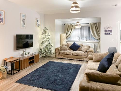 a living room with a couch and a christmas tree at Rothsay Beach House in Newbiggin-by-the-Sea