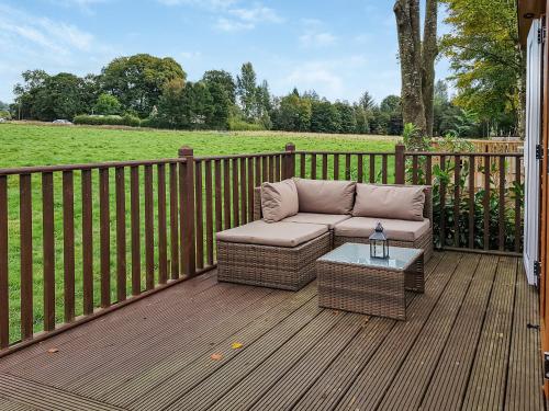 a patio with a couch and a table on a deck at Glenbeagles Lodge in Dollar