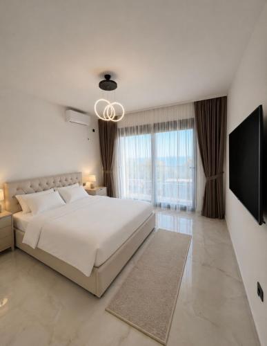 a white bedroom with a large bed and a flat screen tv at Villa Deromano in Šušanj