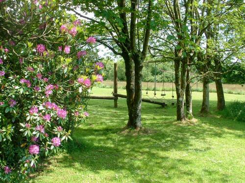 a park with trees and pink flowers and a fence at The Garden Lodge Flat - Uk49415 in Pembrokeshire