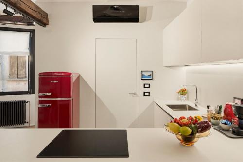 a kitchen with a red refrigerator and a bowl of fruit on a counter at Iseo Vicolo Portelle - indoor private parking & bike storage in Iseo
