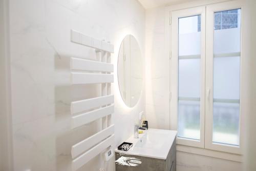a white bathroom with a sink and a mirror at BM Apartamentos in Ribadesella