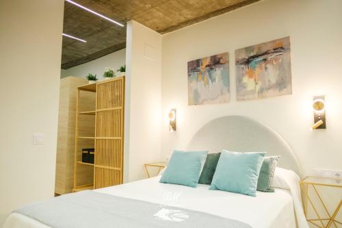 a bedroom with a white bed with blue pillows at BM Apartamentos in Ribadesella
