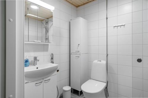 a white bathroom with a toilet and a sink at Hiisi Homes Turku Ratapiha in Turku