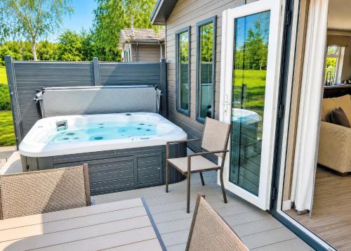a hot tub sitting on a patio with chairs at Bosworth Lakeside Lodges in Carlton