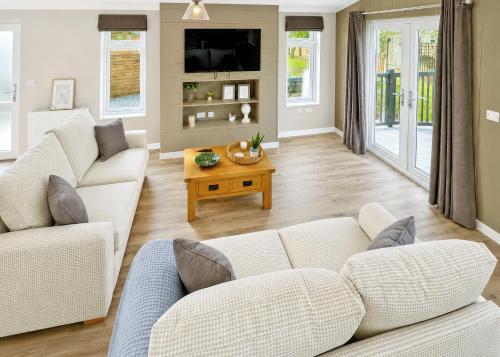 a living room with two white couches and a table at Bosworth Lakeside Lodges in Carlton