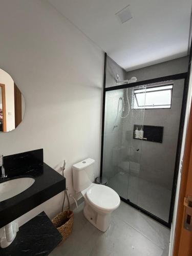 a bathroom with a toilet and a glass shower at Condomínio Bosque da Praia, casa 193 Jacumã RN in Jacumã