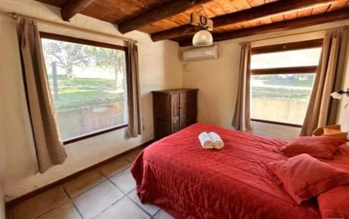 a bedroom with a red bed and a large window at Cabañas Luna Lunera in Tandil