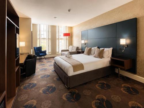 a hotel room with a large bed and a chair at Queens Hotel Belfast in Belfast