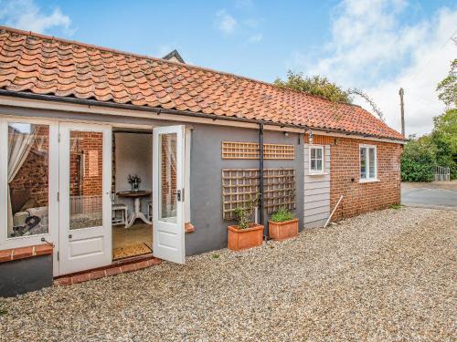 a brick house with a white door and a patio at Barwick Lodge in Bawdeswell