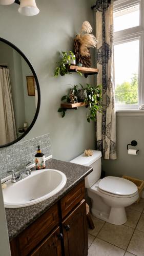 a bathroom with a sink and a toilet and a mirror at Shediac Beach Suite- Pointe du Chene Wharf and Parlee Beach in Pointe-du-Chêne