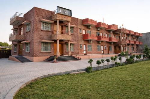 a large red brick building with a lawn in front of it at Udaigarh Palace - The Heritage Hotel in Jodhpur