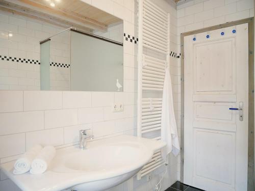 a white bathroom with a sink and a mirror at Poeler Inselhaus in Kaltenhof