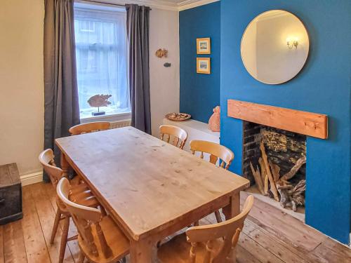 a dining room with a wooden table and a fireplace at Lazy Cottage in Haverigg
