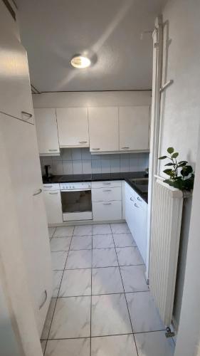 a kitchen with white cabinets and a tile floor at Charmantes Studio in Solothurn