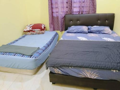 two beds sitting next to each other in a bedroom at Rumah Kuning Homestay in Bachok