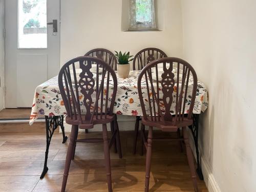 a table with four chairs and a table with a tablecloth on it at Emily's Cottage in Hebden