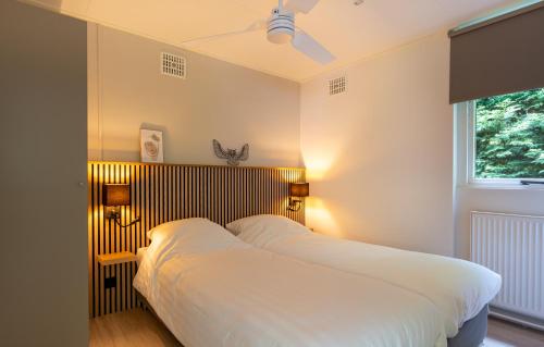 a bedroom with a bed with white sheets and a window at De Vlinderstruik | 4 persons in Gasselte
