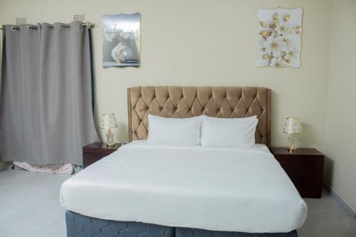 a bedroom with a large white bed with two night stands at Monga's Apartments in Ndola