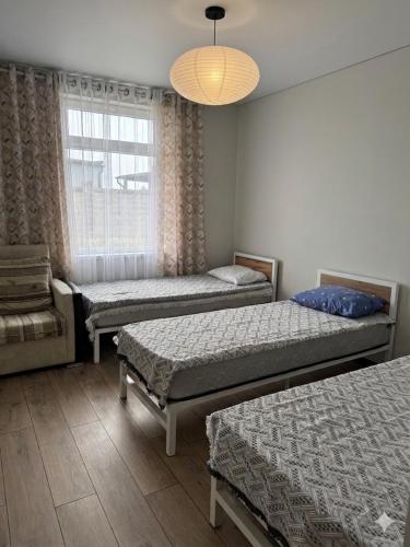 a room with three beds and a window at Квартиры под соснами in Cholpon-Ata