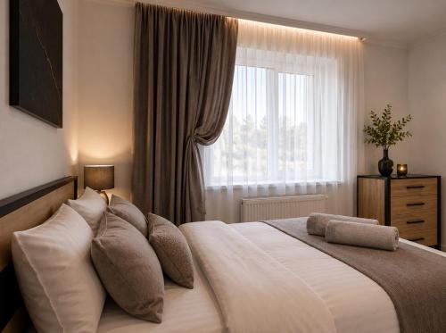 a bedroom with a large white bed with a window at Апартаменти 2-кім Тарнавського in Ternopil