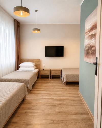 a room with two beds and a flat screen tv at Apartament Contra II in Wodzisław Śląski