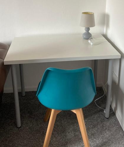 a white desk with a blue chair in a room at Great for commuting, budget friendly apartment in Dalmuir