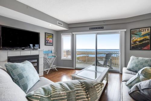a living room with a couch and a tv and a balcony at Playa Flamingo #302 in Ocean City