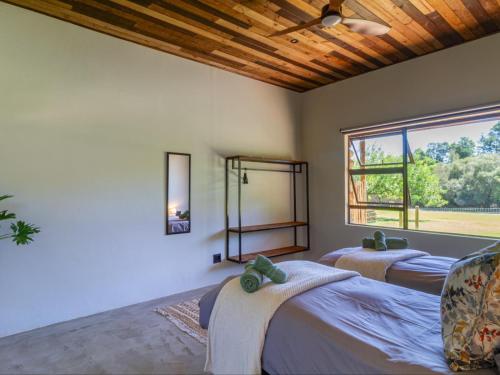 a bedroom with two beds and a large window at Wild Olive Cottage with Hot tub in Wolseley