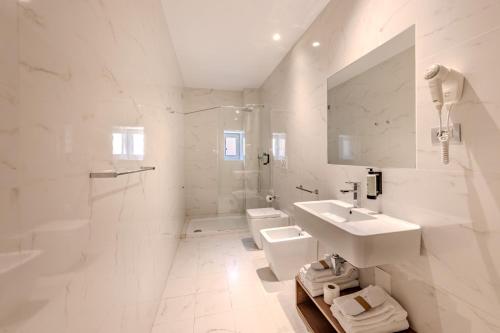 a white bathroom with a sink and a toilet at HNN Luxury Suites in Genoa