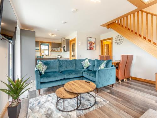 a living room with a blue couch and a table at The Larches - Uk46804 in Culbokie