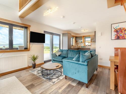 a living room with a blue couch and a table at The Larches - Uk46804 in Culbokie
